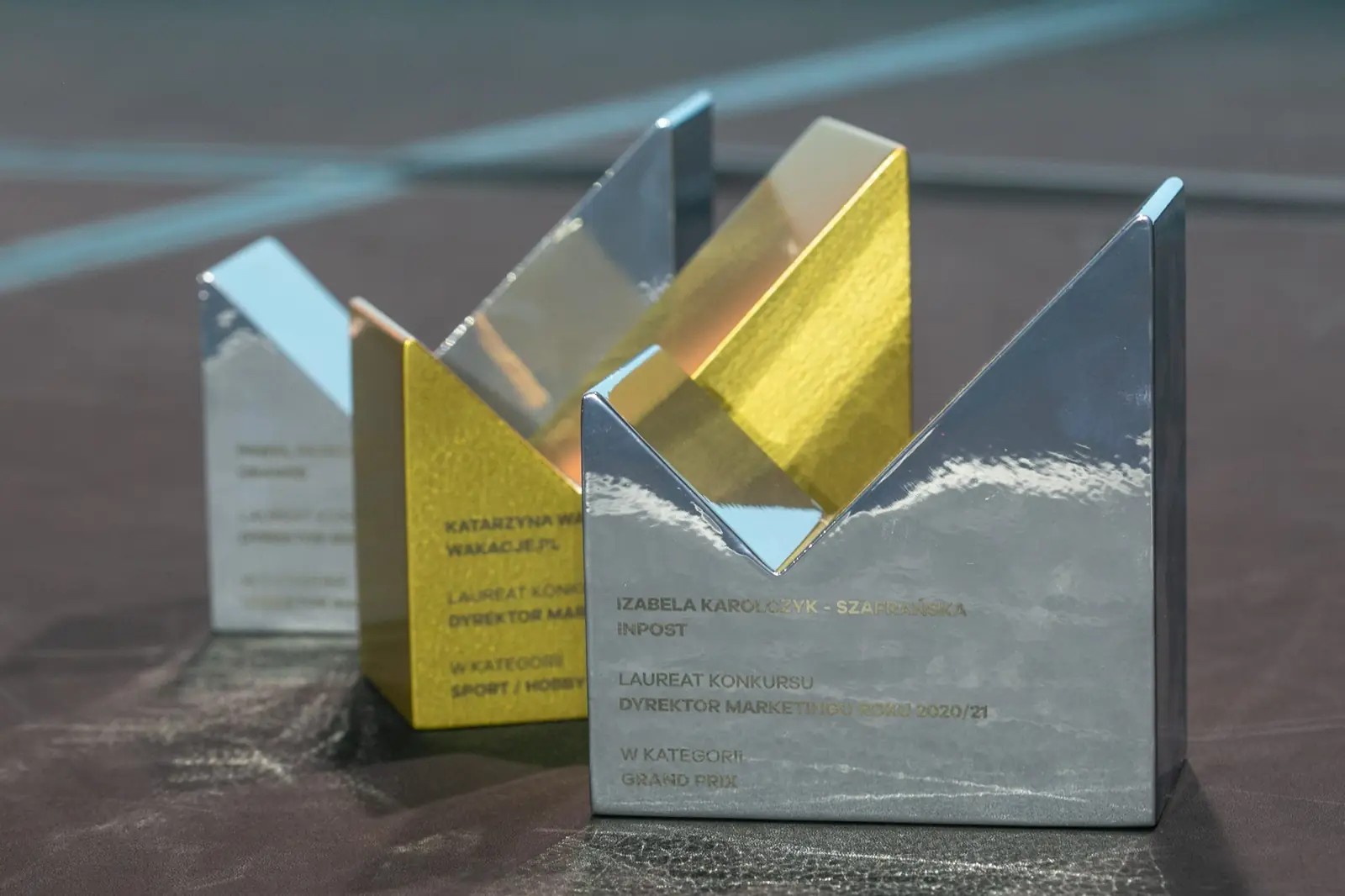 Close-up of silver and golden M-shaped statuettes standing on a table — DMR Gala X (2021)