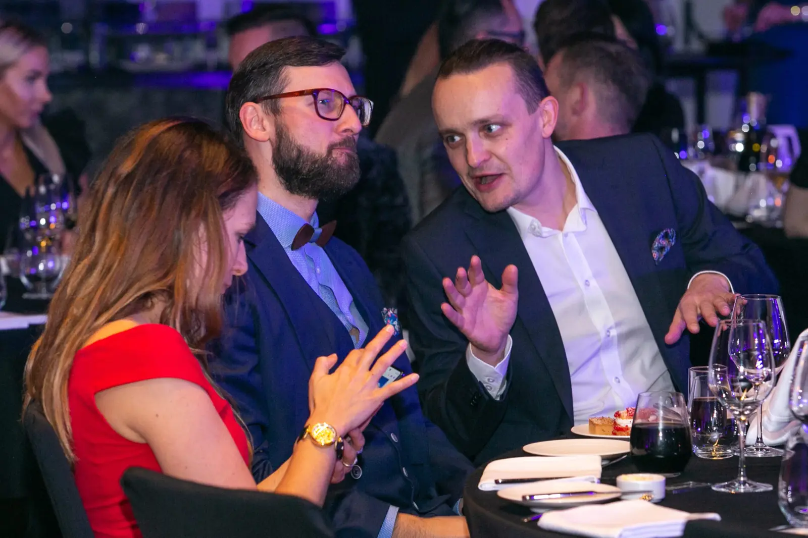 Guests at a table deep in lively conversation, one man gesturing animatedly — DMR Gala X (2021)