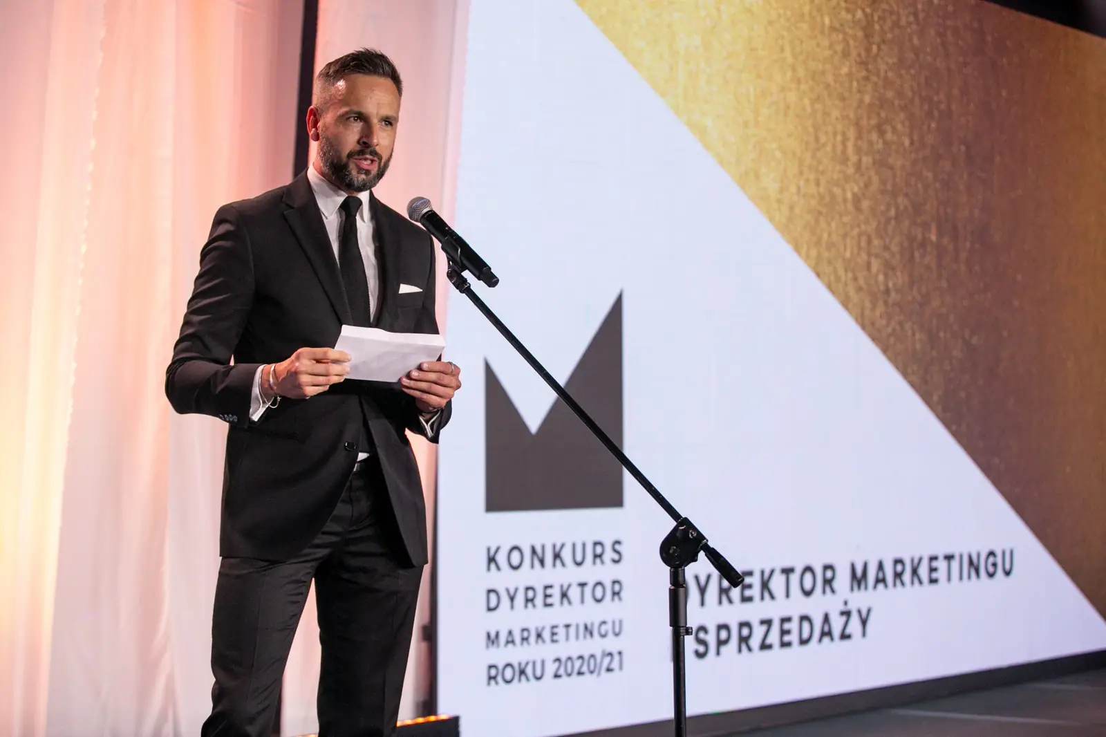 Presenter in a black suit announces the Marketing and Sales Director award — DMR Gala X (2021)