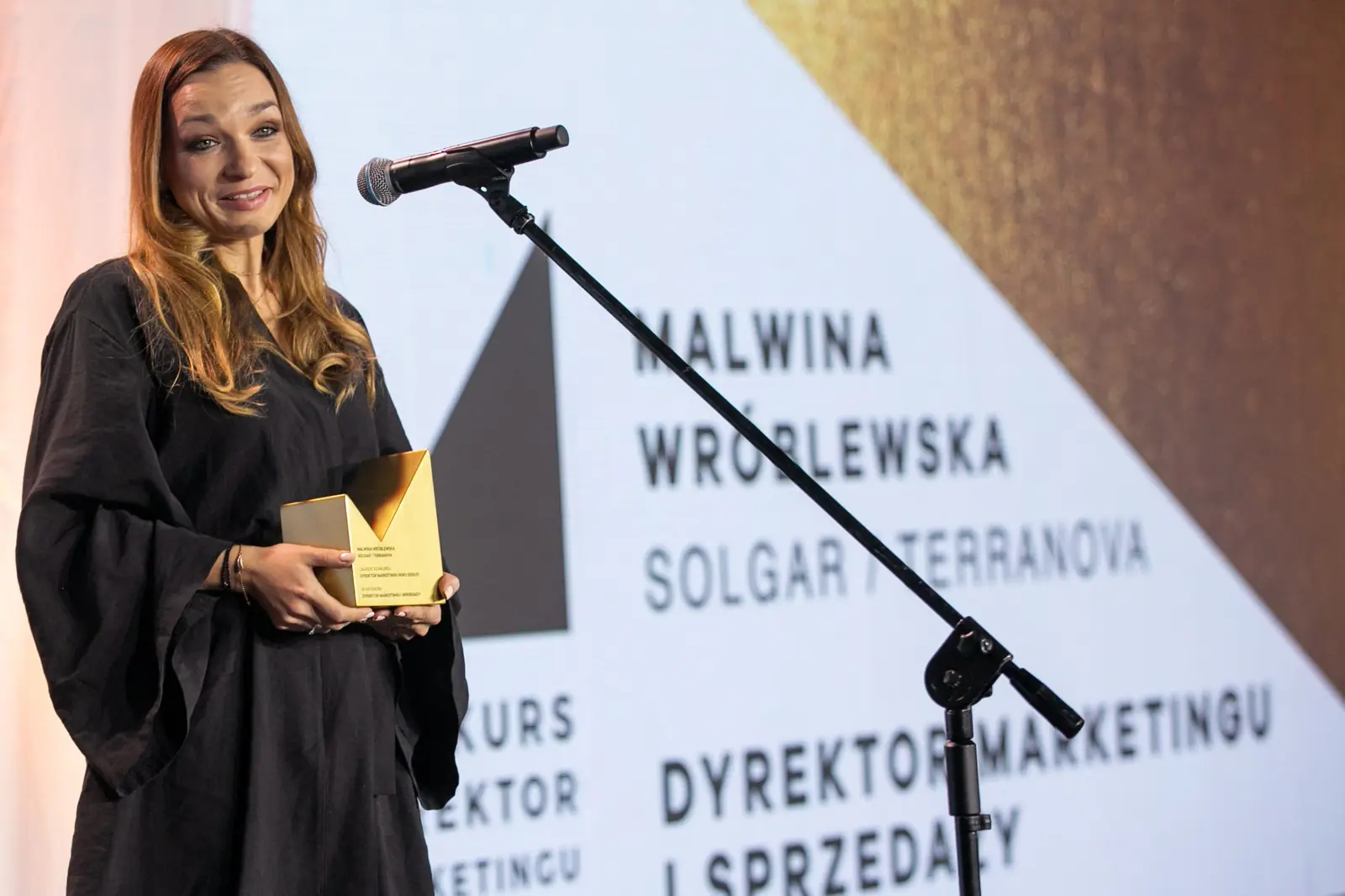 Winner of the Marketing and Sales Director award poses with her statuette by the microphone — DMR Gala X (2021)