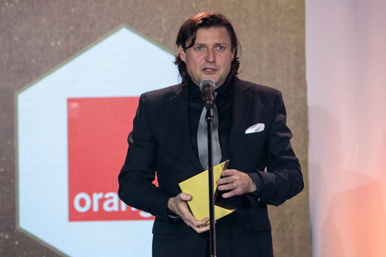Laureat nagrody za wieloletnie osiągnięcia, z długimi włosami, przemawia przy mikrofonie — Gala DMR X (2021)