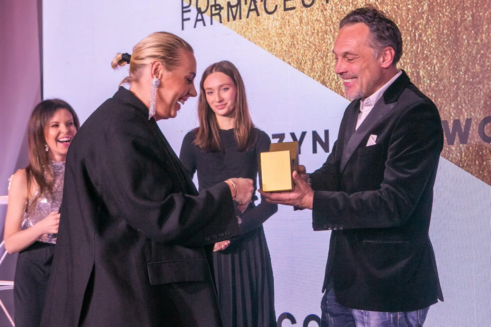 Laureatka w czarnej marynarce odbiera statuetkę od uśmiechniętego wręczającego — Gala DMR X (2021)