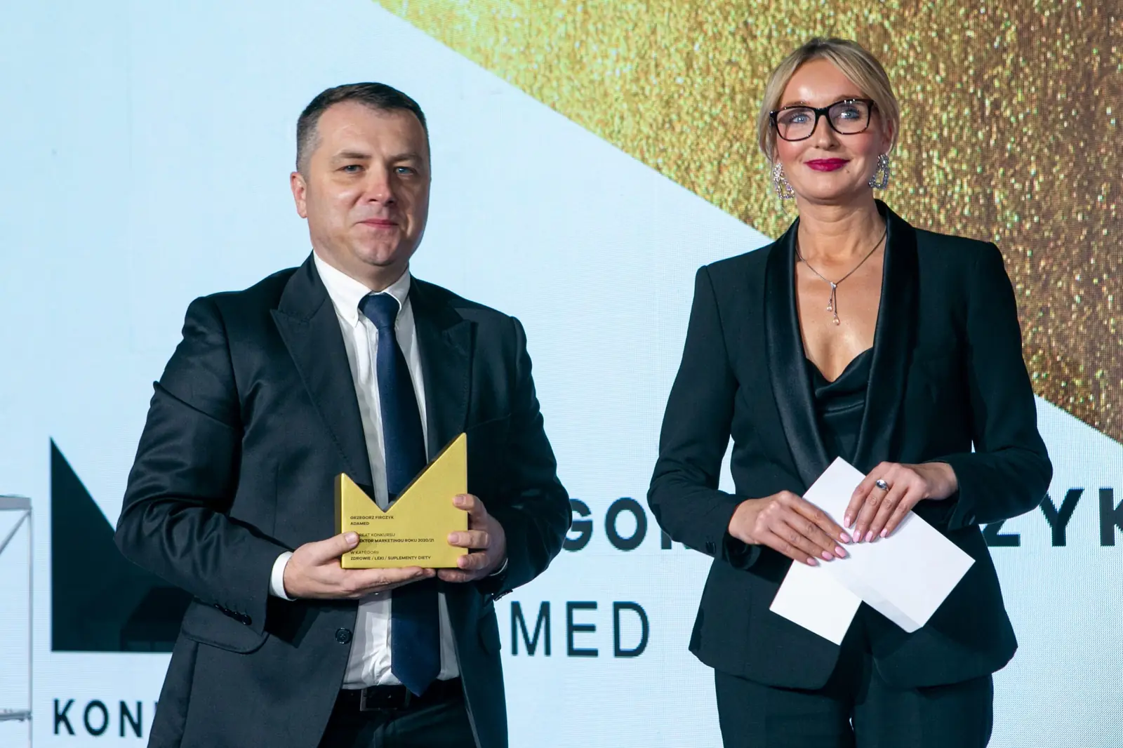 Winner with a statuette and the presenter holding an envelope pose before the screen — DMR Gala X (2021)