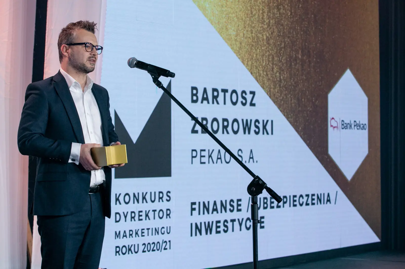 Winner in the finance, insurance and investment category stands at the microphone with a statuette — DMR Gala X (2021)