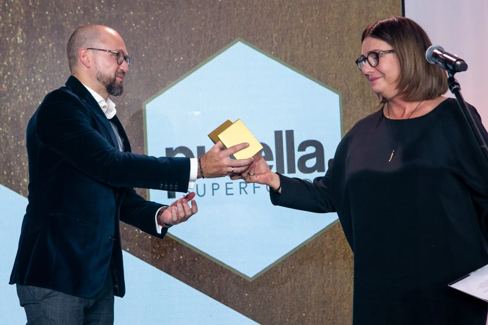 Laureat w okularach przyjmuje statuetkę od wręczającej w kategorii produkty spożywcze — Gala DMR X (2021)