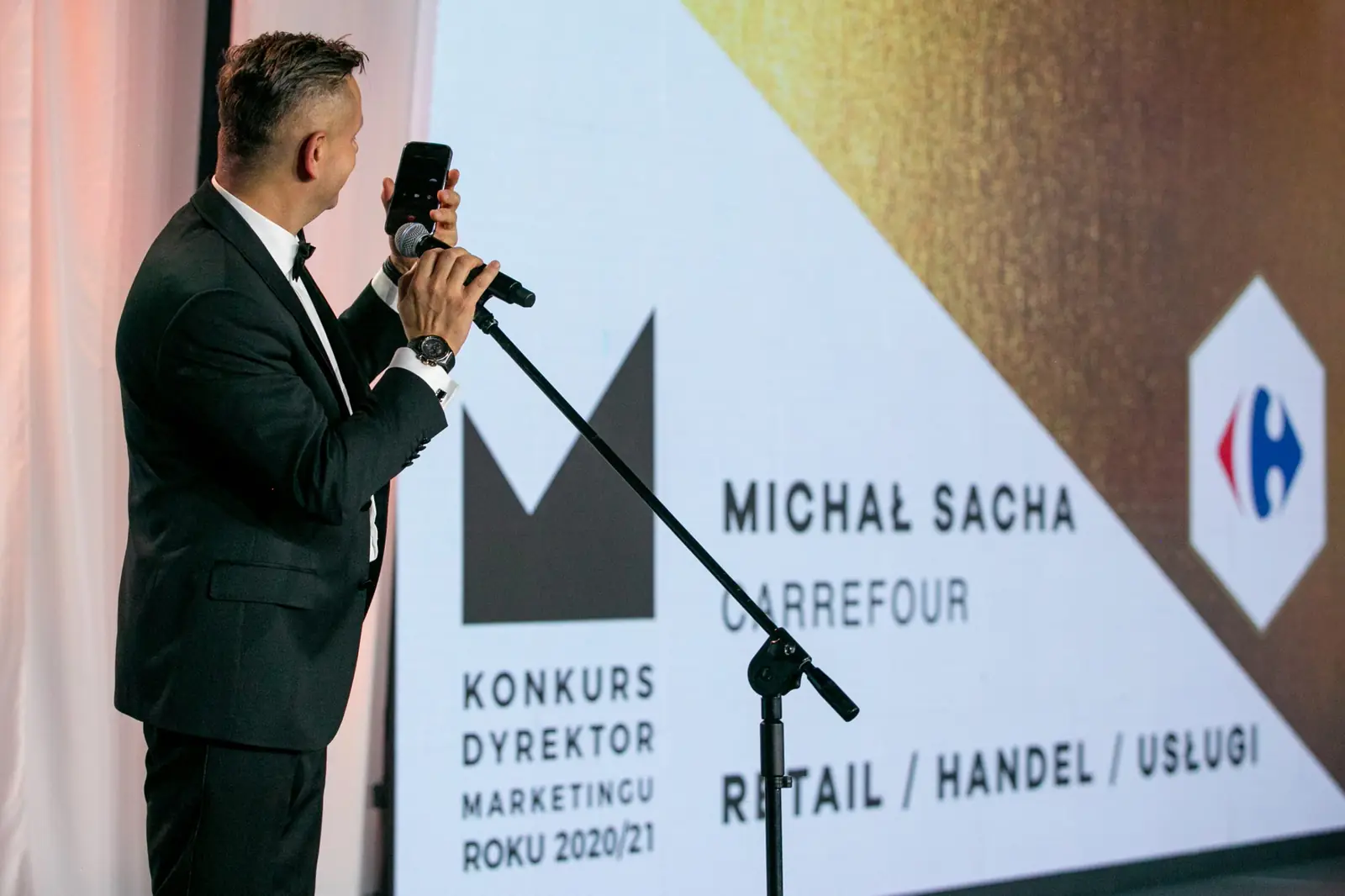 Host holds a phone up to the stand microphone during a live call — DMR Gala X (2021)