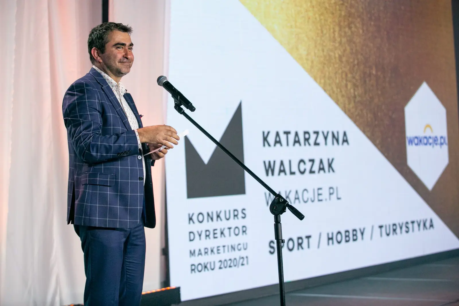 Presenter in a navy checked blazer announces the sport, hobby and travel category — DMR Gala X (2021)