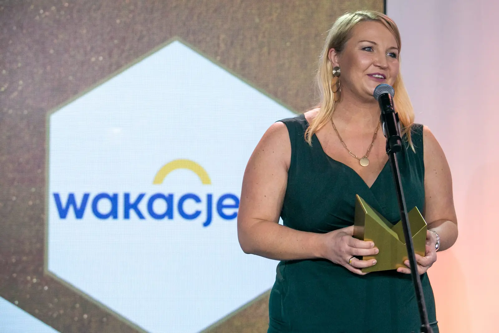 Smiling winner in a dark green dress speaks at the microphone — DMR Gala X (2021)