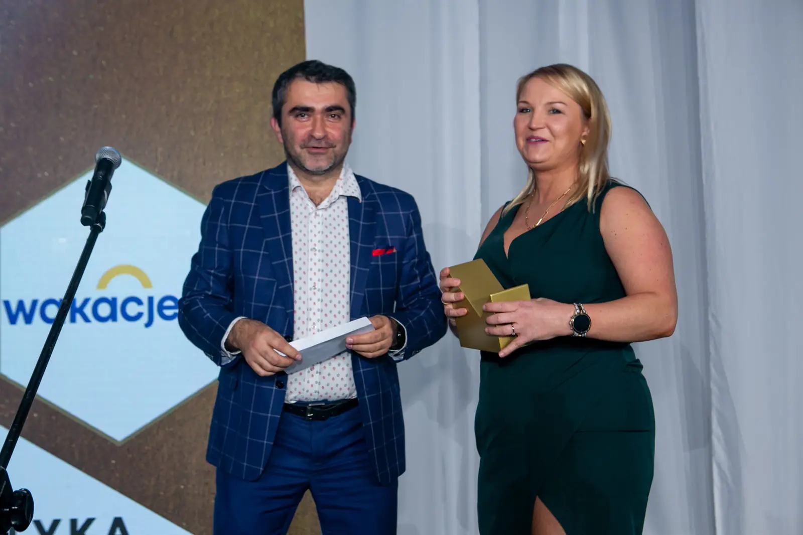Laureatka w zielonej sukience ze statuetką i wręczający w marynarce w kratę uśmiechają się — Gala DMR X (2021)