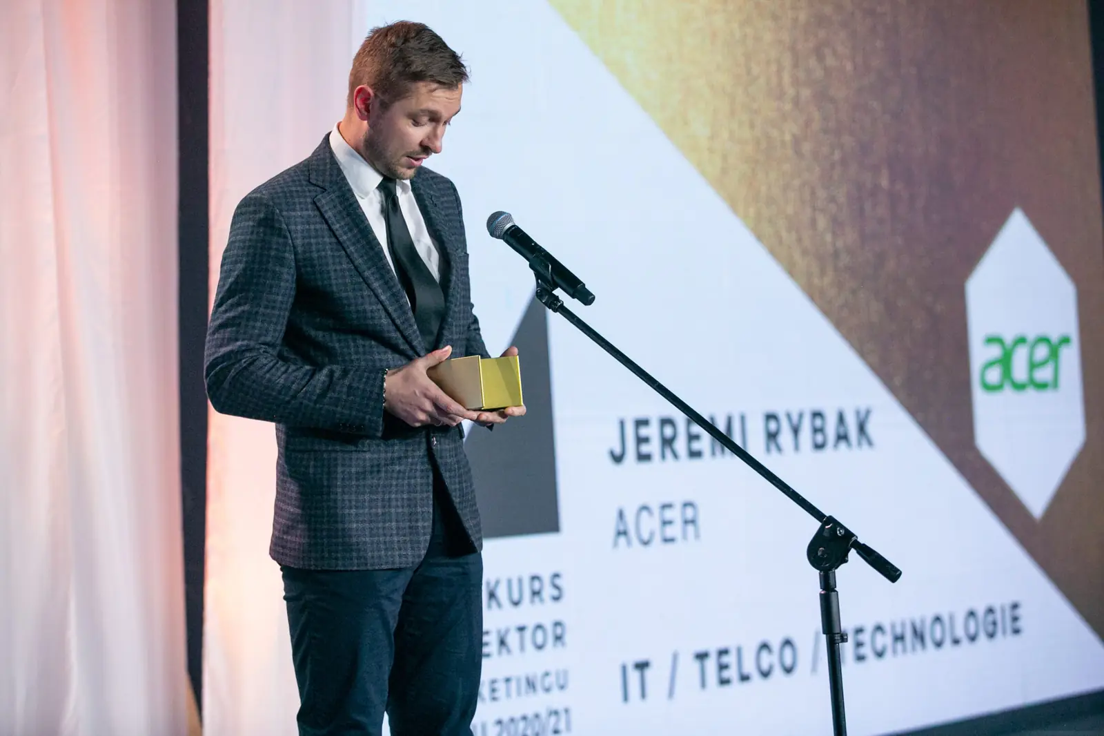 Laureat w kategorii IT, telco i technologie stoi przy mikrofonie ze statuetką — Gala DMR X (2021)