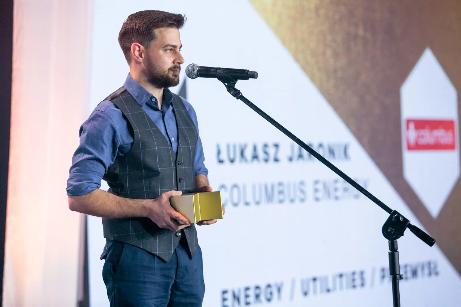 Laureat w kategorii energia, utilities i przemysł stoi ze statuetką przy mikrofonie — Gala DMR X (2021)