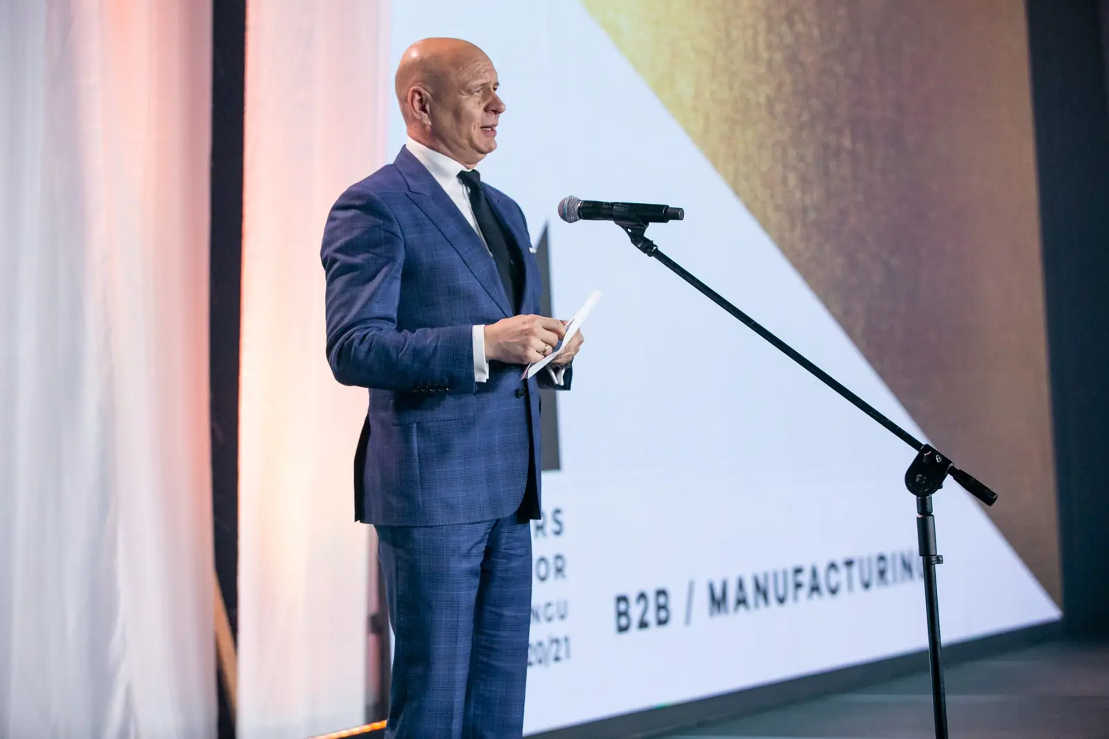 Wręczający w granatowym garniturze w kratę zapowiada kategorię B2B i manufacturing — Gala DMR X (2021)