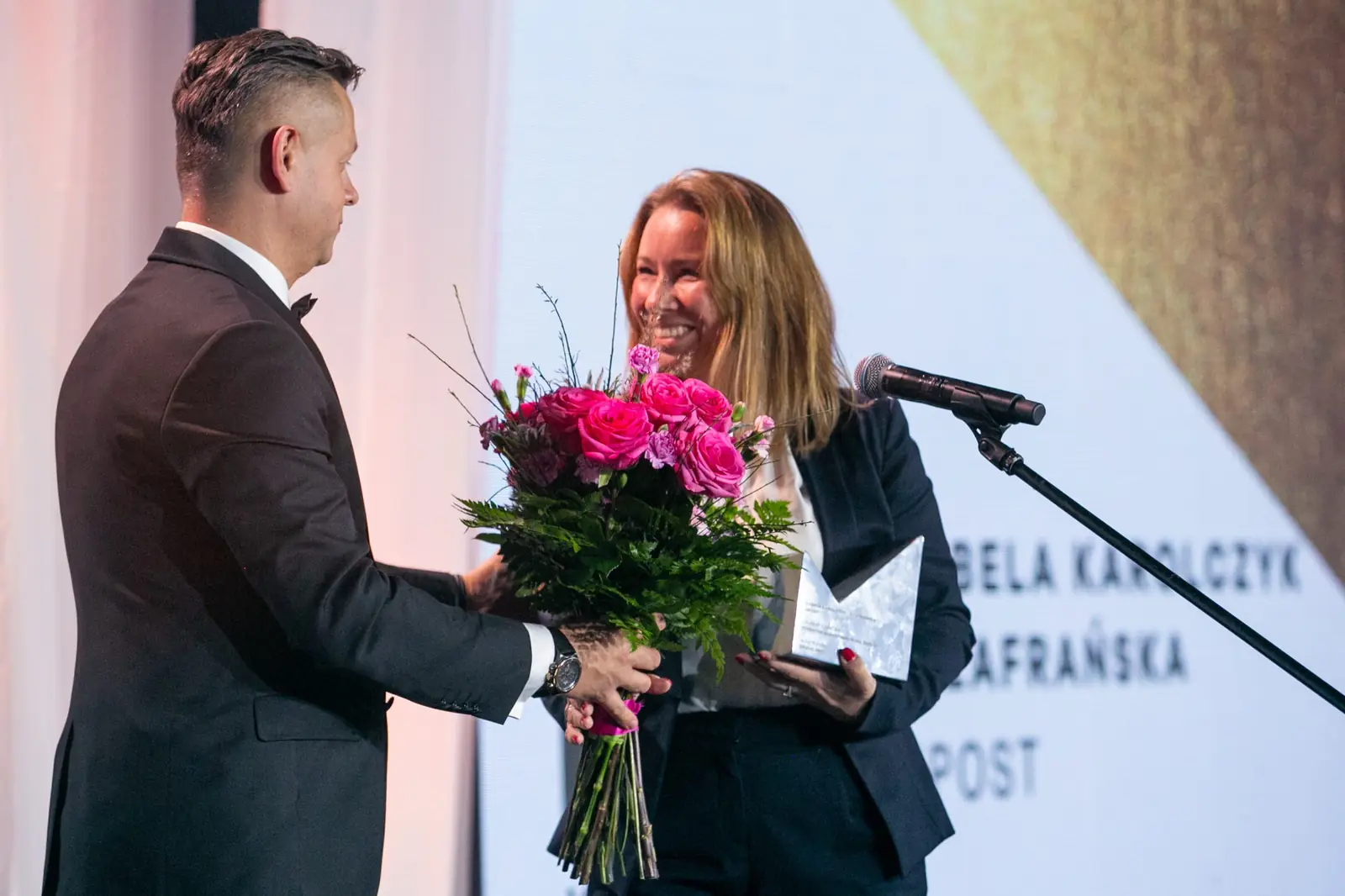 Host hands the winner a bouquet of pink roses and she bursts out laughing — DMR Gala X (2021)