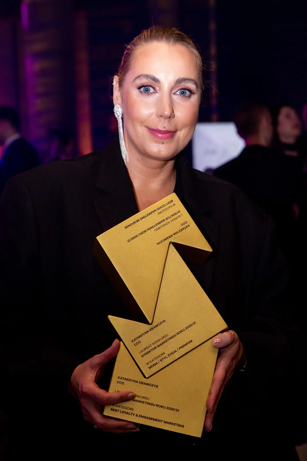 Winner with slicked-back hair holds two golden statuettes stacked one above the other — DMR Gala X (2021)
