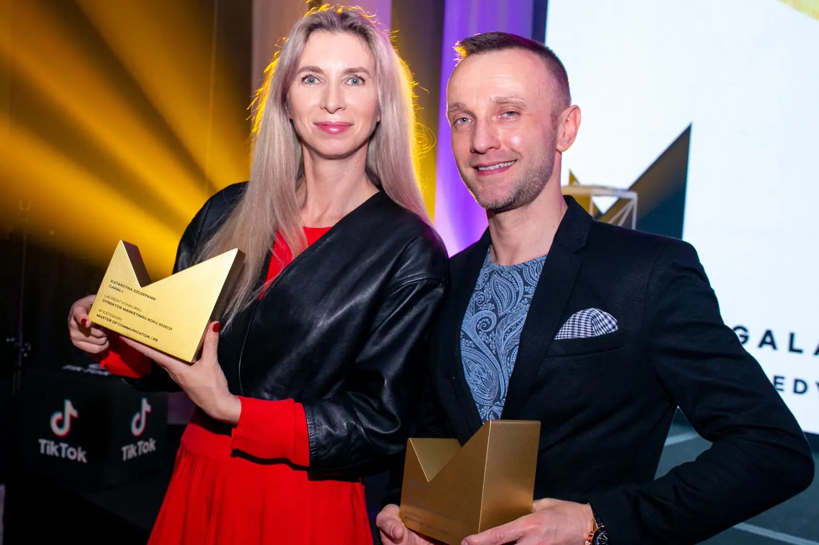 Laureatka w czerwonej sukience i laureat z poszetką pozują razem ze statuetkami — Gala DMR X (2021)