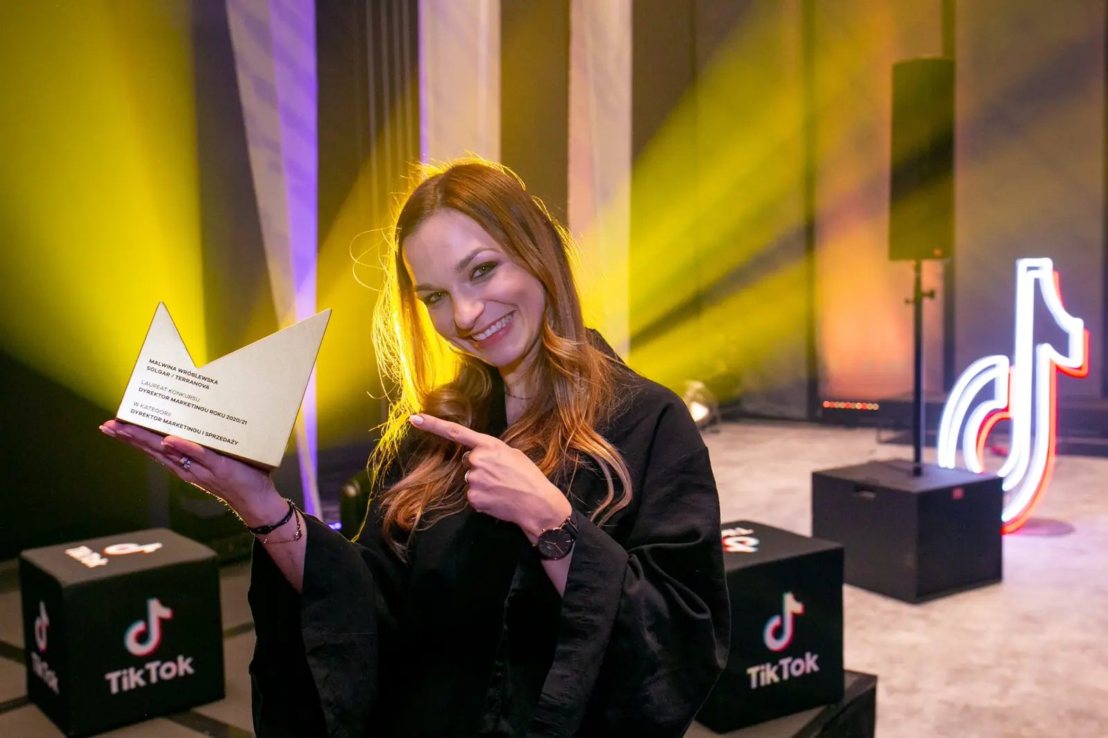 Smiling winner points at the golden statuette she is holding — DMR Gala X (2021)