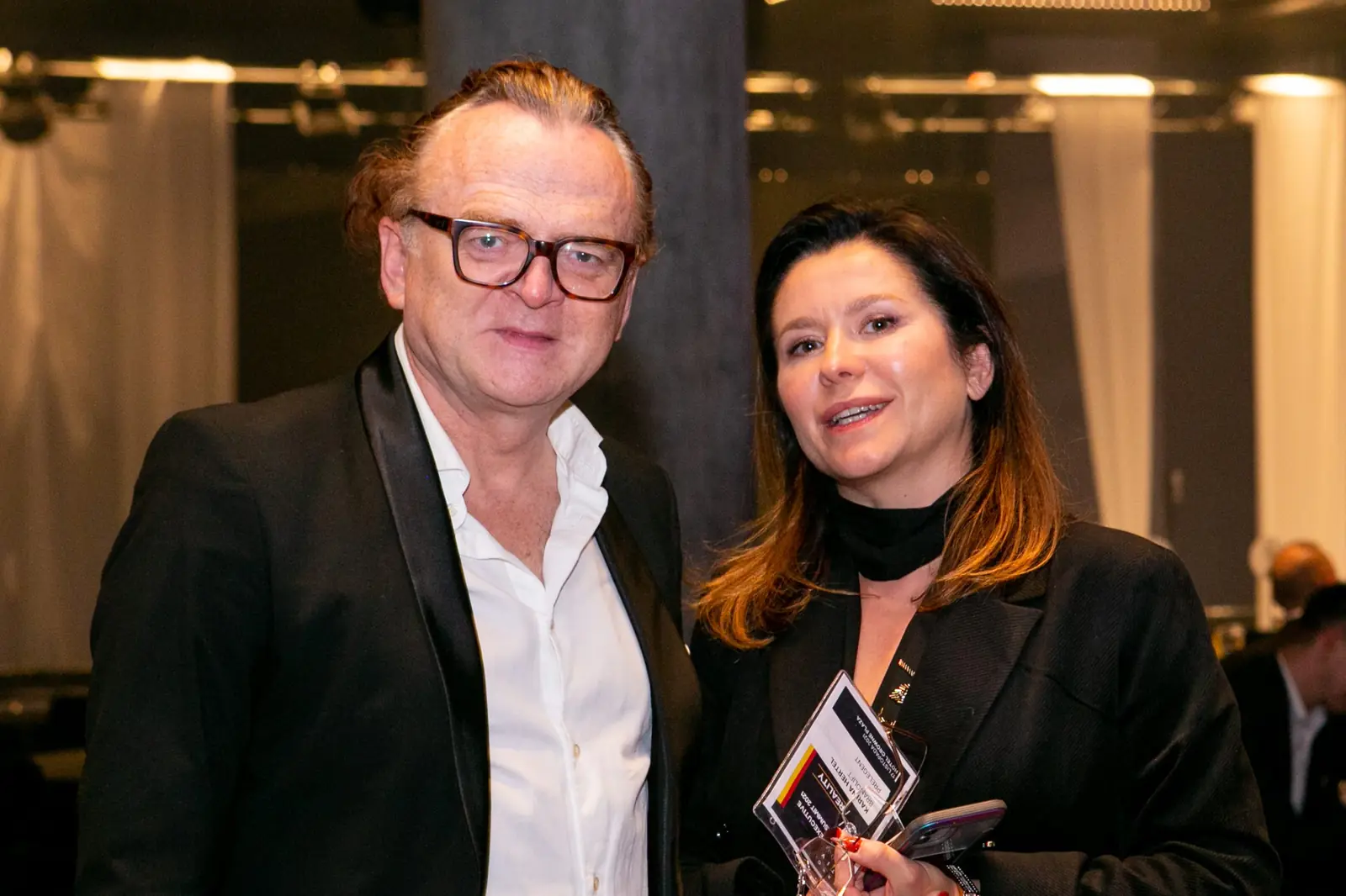 Man in glasses and a woman in black pose together among the gala guests — DMR Gala X (2021)