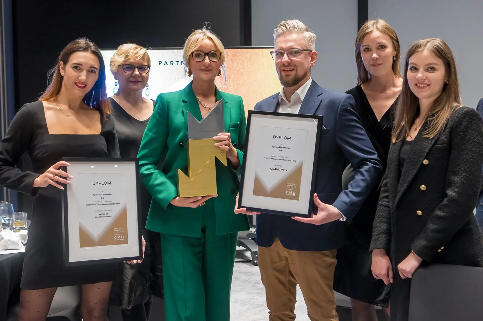 Sześcioosobowy zespół z dwoma dyplomami i złotą statuetką pozuje w sali bankietowej — Gala DMR XI (2022)