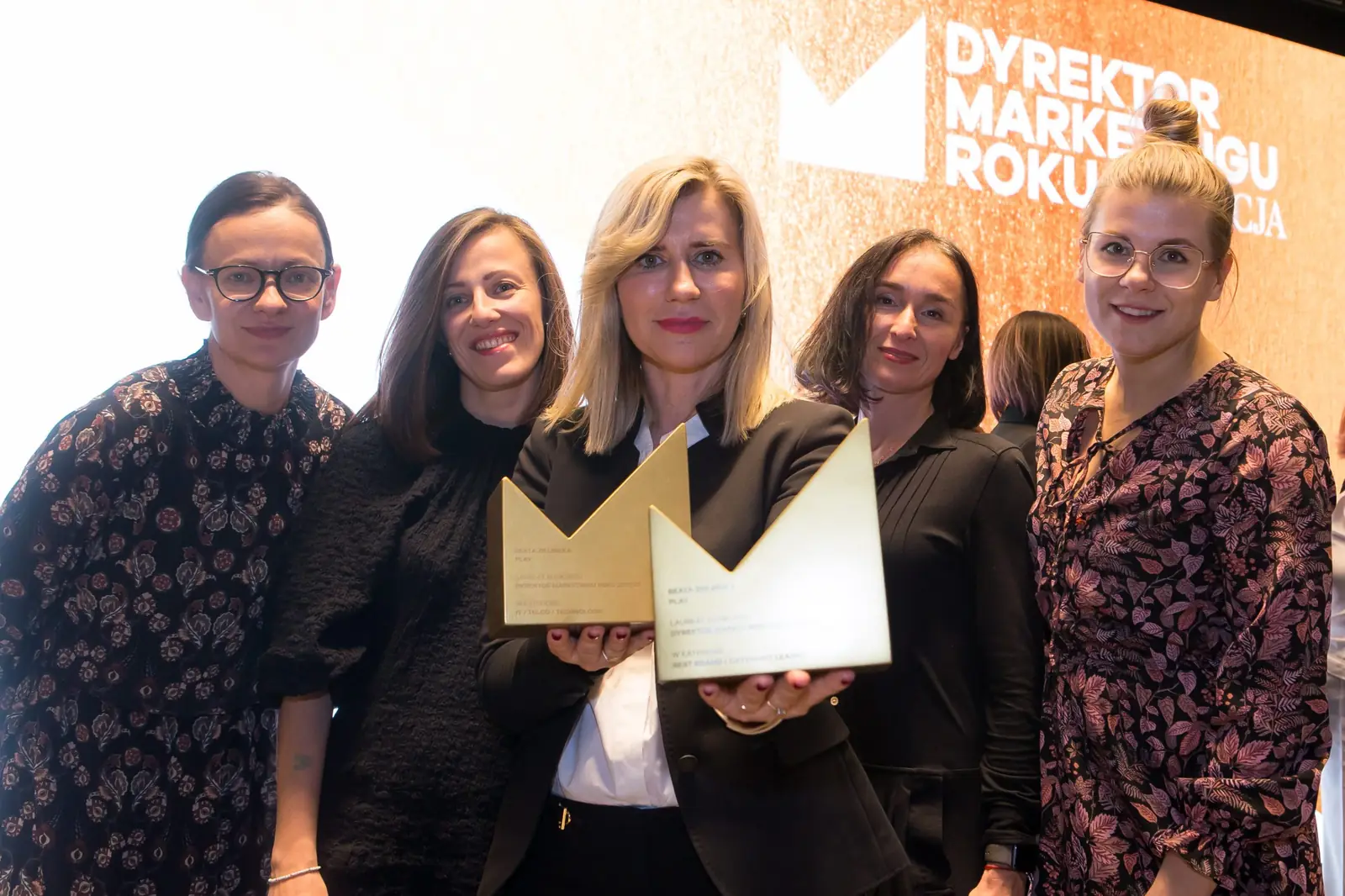 Pięć uśmiechniętych kobiet tłoczy się wokół laureatki z dwiema złotymi statuetkami — Gala DMR XI (2022)