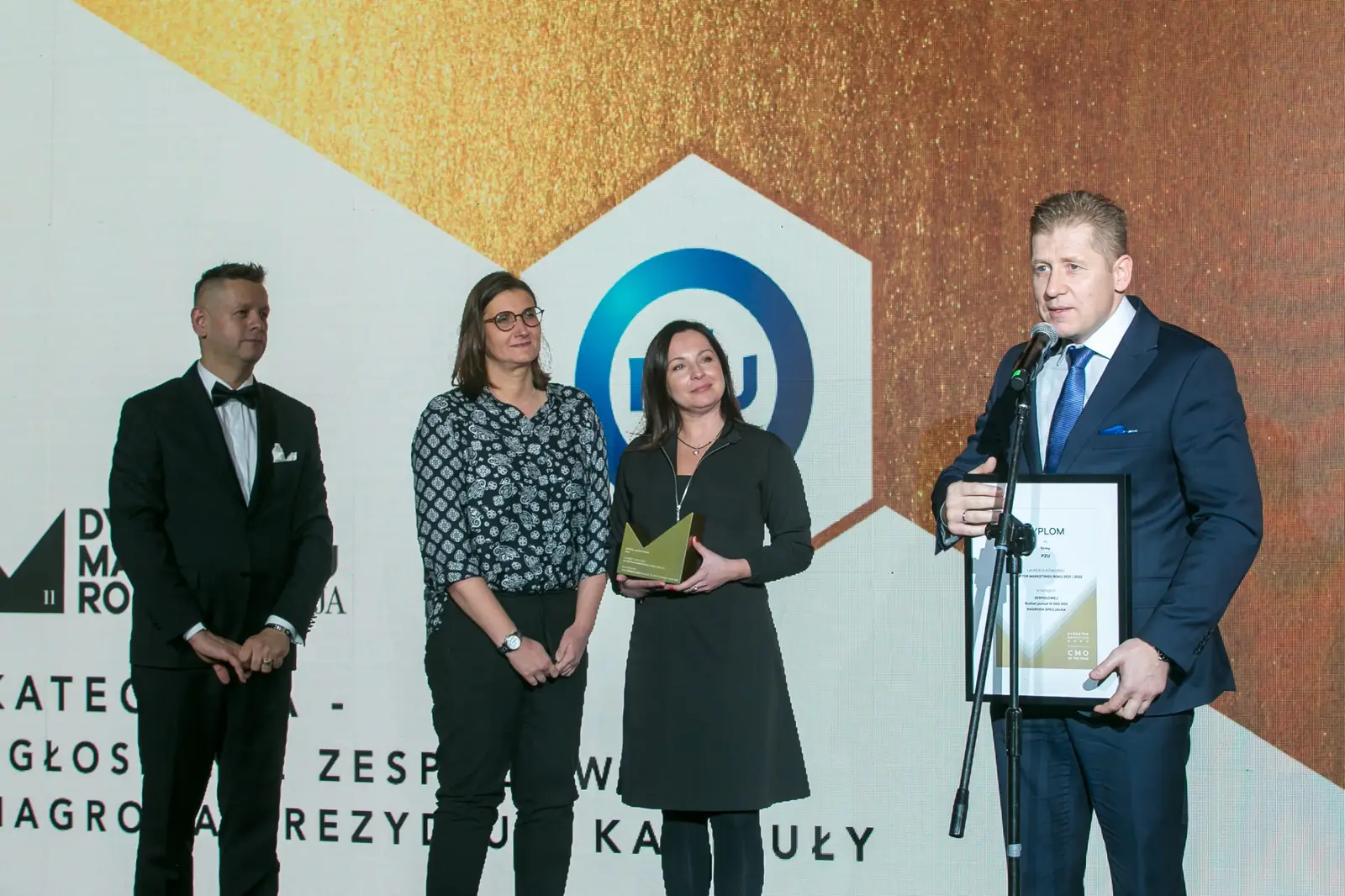 Nagroda Prezydium Kapituły w kategorii zespołowej: laureat dziękuje, obok laureatki ze statuetką — Gala DMR XI (2022)