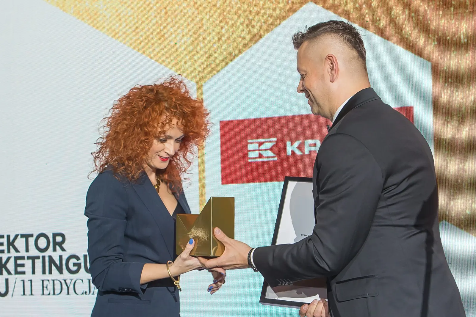 Laureatka z burzą rudych loków odbiera złotą statuetkę z rąk prowadzącego — Gala DMR XI (2022)
