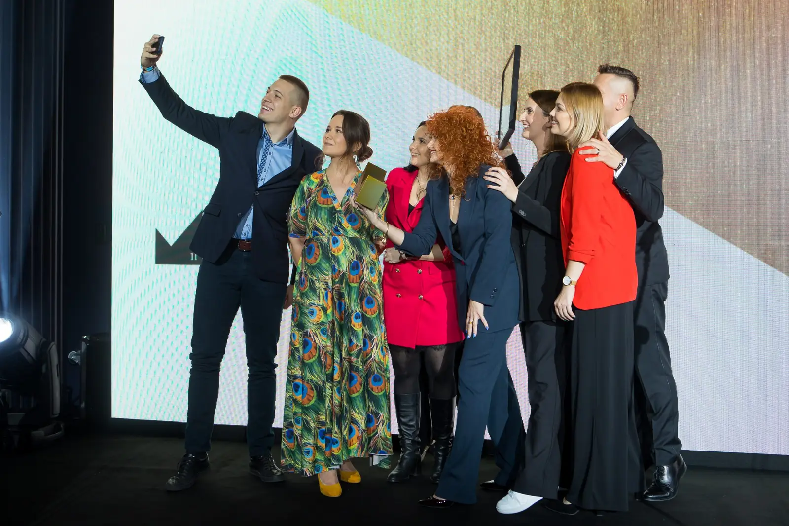 Członek zespołu robi grupowe selfie z rudowłosą laureatką i koleżankami na scenie — Gala DMR XI (2022)