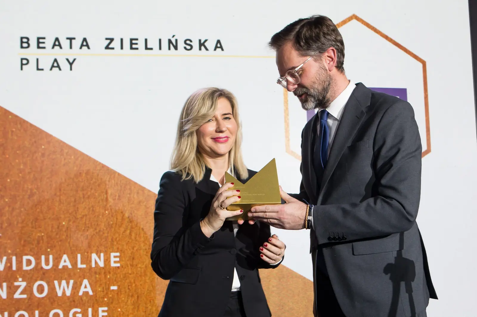 Laureatka w czarnym żakiecie z uśmiechem przyjmuje złotą statuetkę w kategorii technologie — Gala DMR XI (2022)