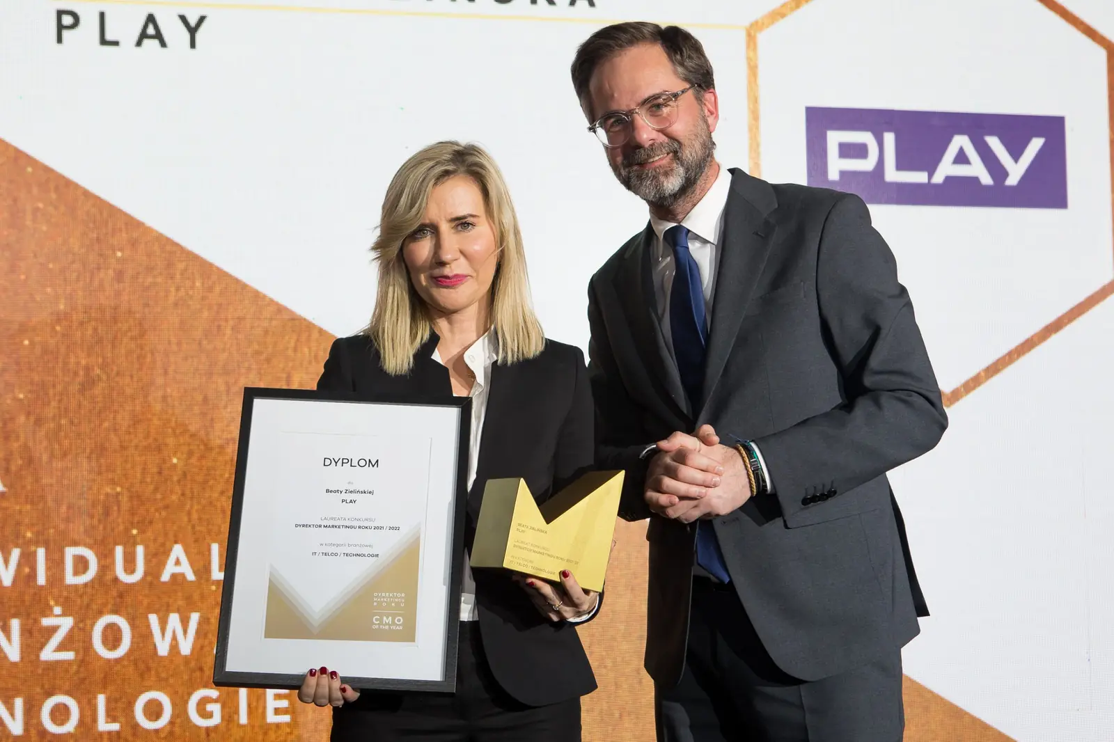 Laureatka z dyplomem i statuetką pozuje z wręczającym nagrodę mężczyzną w okularach — Gala DMR XI (2022)