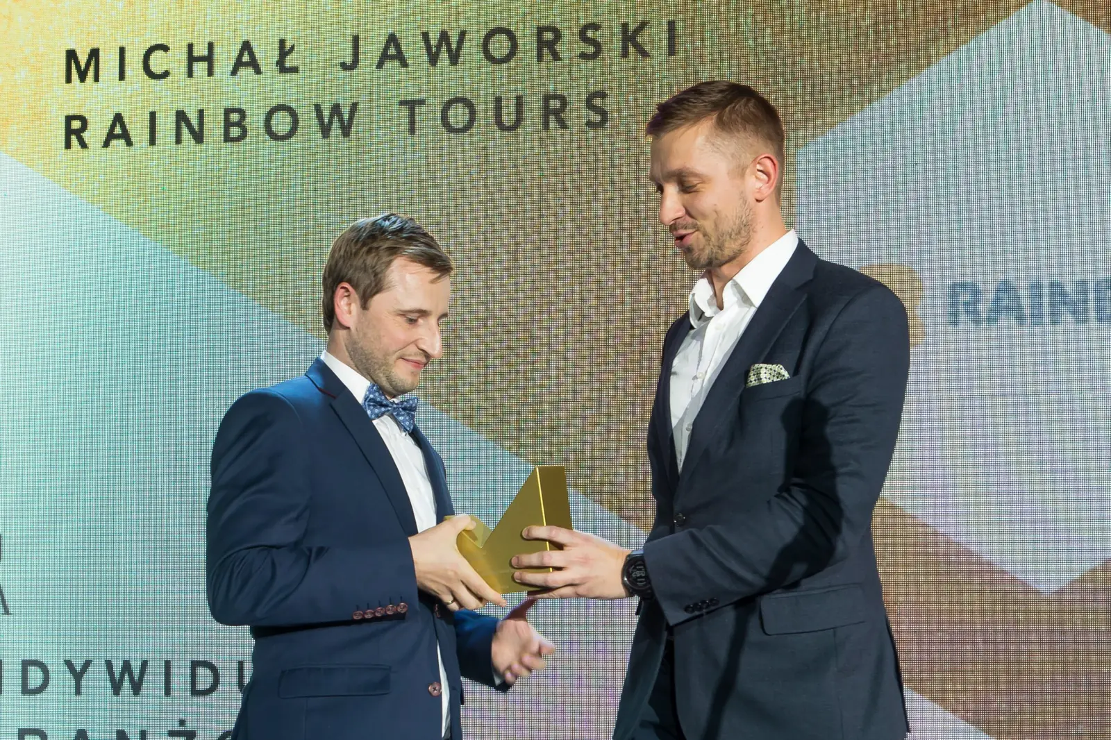 Laureat z muszką odbiera złotą statuetkę od wręczającego w granatowym garniturze — Gala DMR XI (2022)