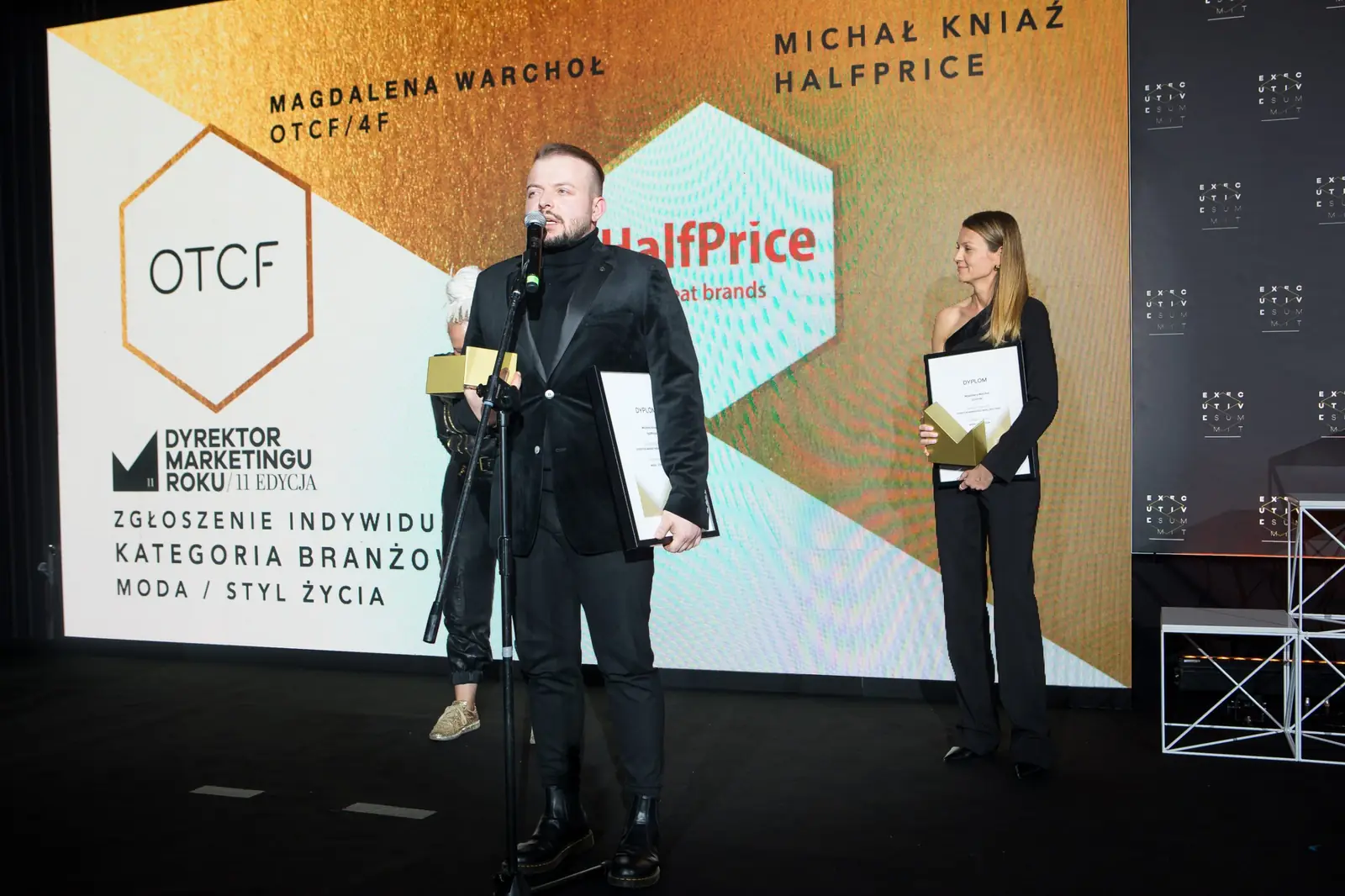 Dwoje laureatów kategorii moda i styl życia na scenie, laureat mówi do mikrofonu na statywie — Gala DMR XI (2022)