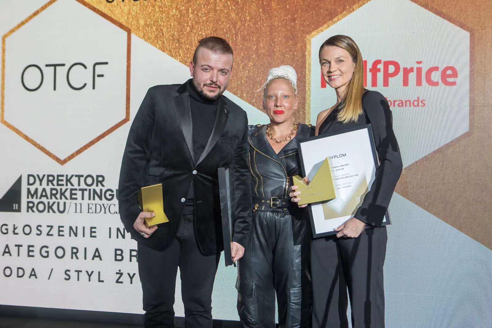 Kobieta z platynowymi dredami pozuje z dwojgiem laureatów trzymających dyplom i statuetki — Gala DMR XI (2022)