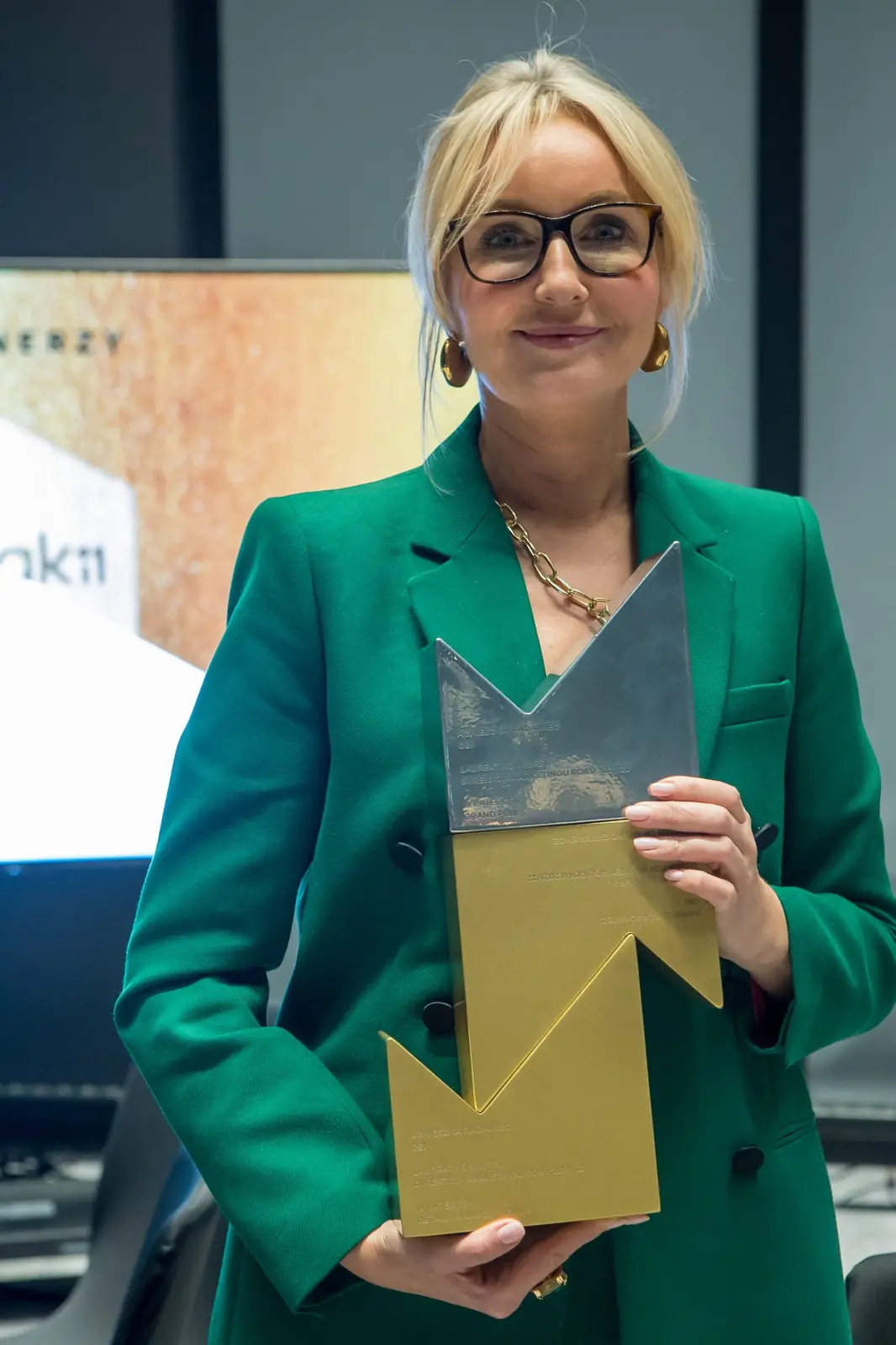 Laureatka Grand Prix w zielonym garniturze i okularach pozuje ze szklaną i złotą statuetką — Gala DMR XI (2022)