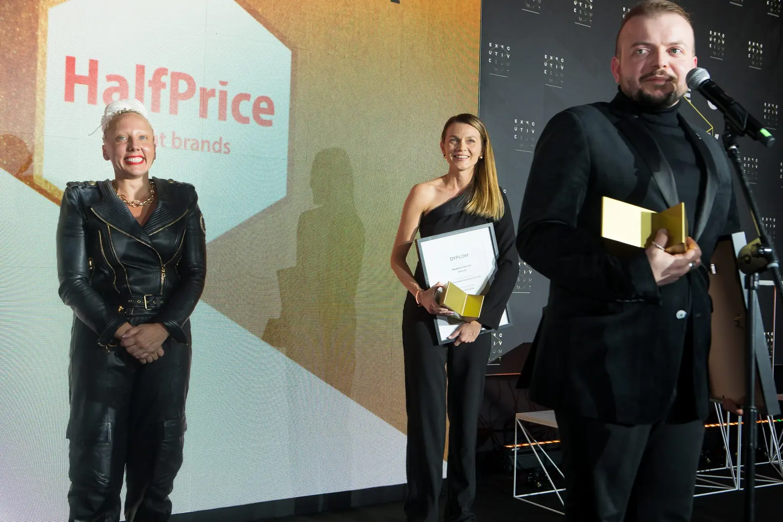 Laureat w czarnej marynarce mówi do mikrofonu, obok laureatka z dyplomem i wręczająca — Gala DMR XI (2022)
