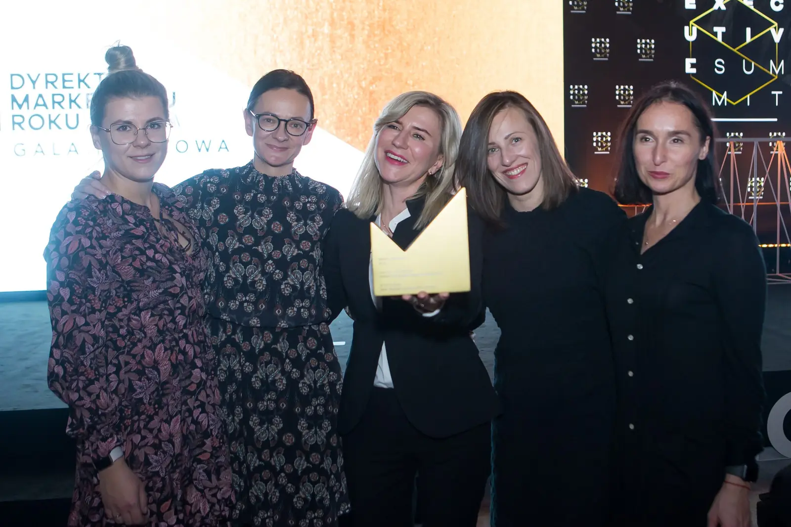 Pięć kobiet w czerni pozuje ze złotą statuetką przed ścianką gali — Gala DMR XI (2022)