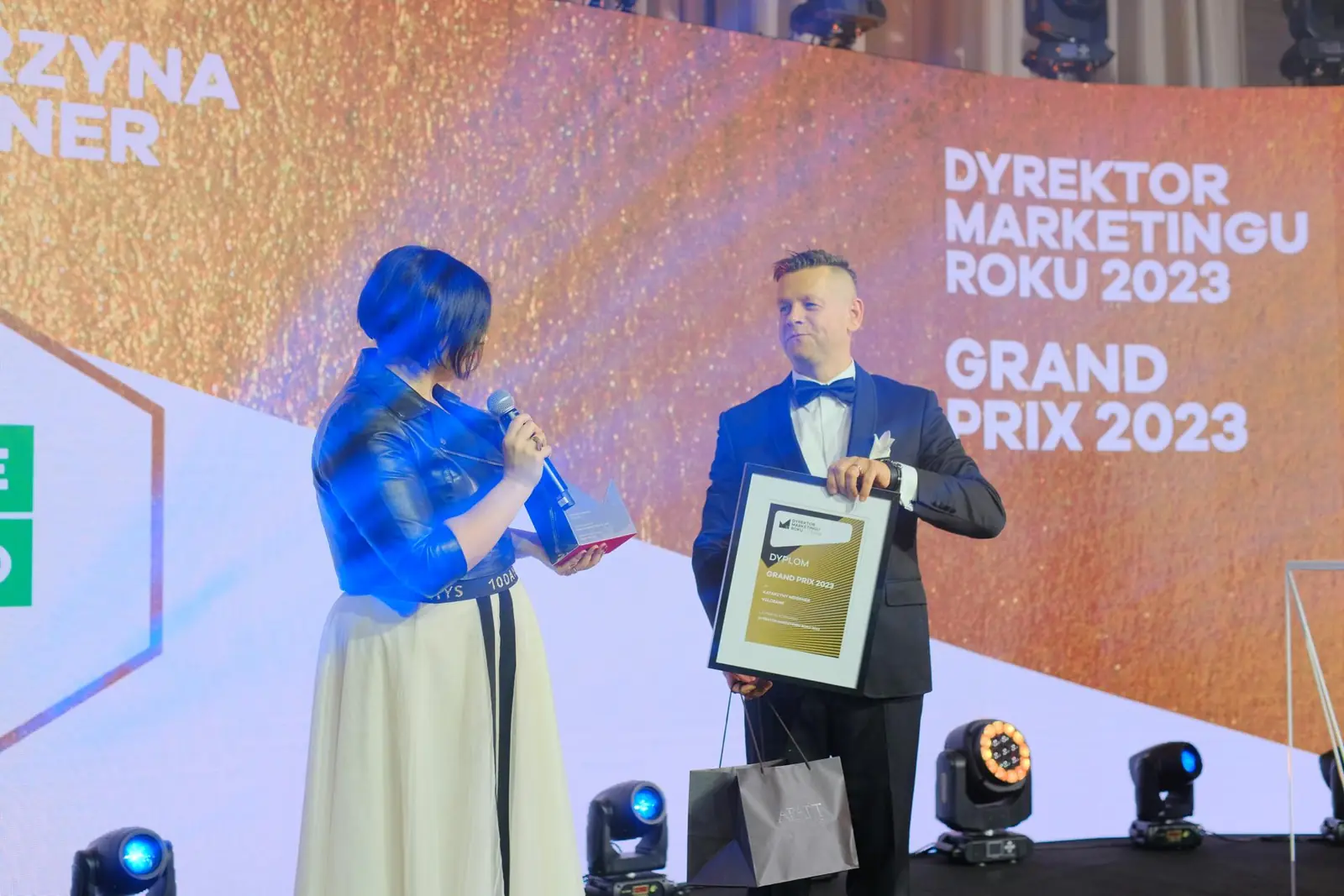 Laureatka Grand Prix dziękuje ze sceny, a prowadzący trzyma dla niej oprawiony dyplom — Gala DMR XII (2023)