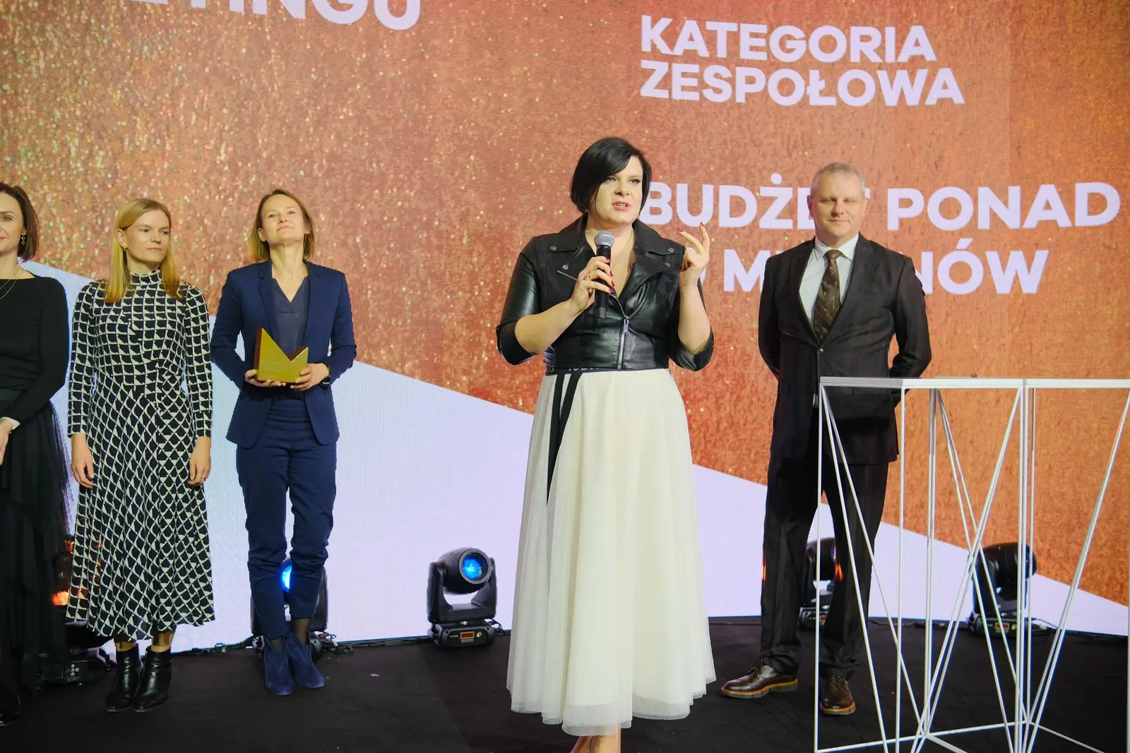 Laureatka w tiulowej spódnicy przemawia w imieniu zespołu nagrodzonego w kategorii zespołowej — Gala DMR XII (2023)