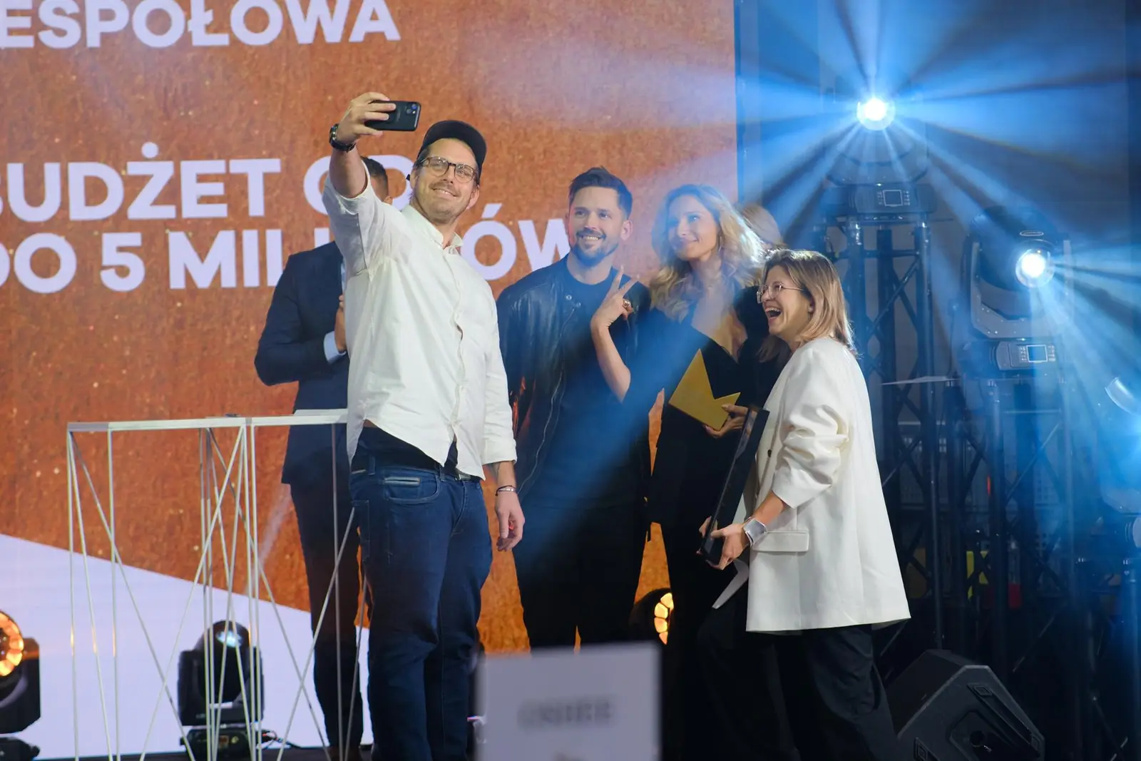 Laureat robi selfie z zespołem na scenie, a koleżanka w białej marynarce wybucha śmiechem — Gala DMR XII (2023)