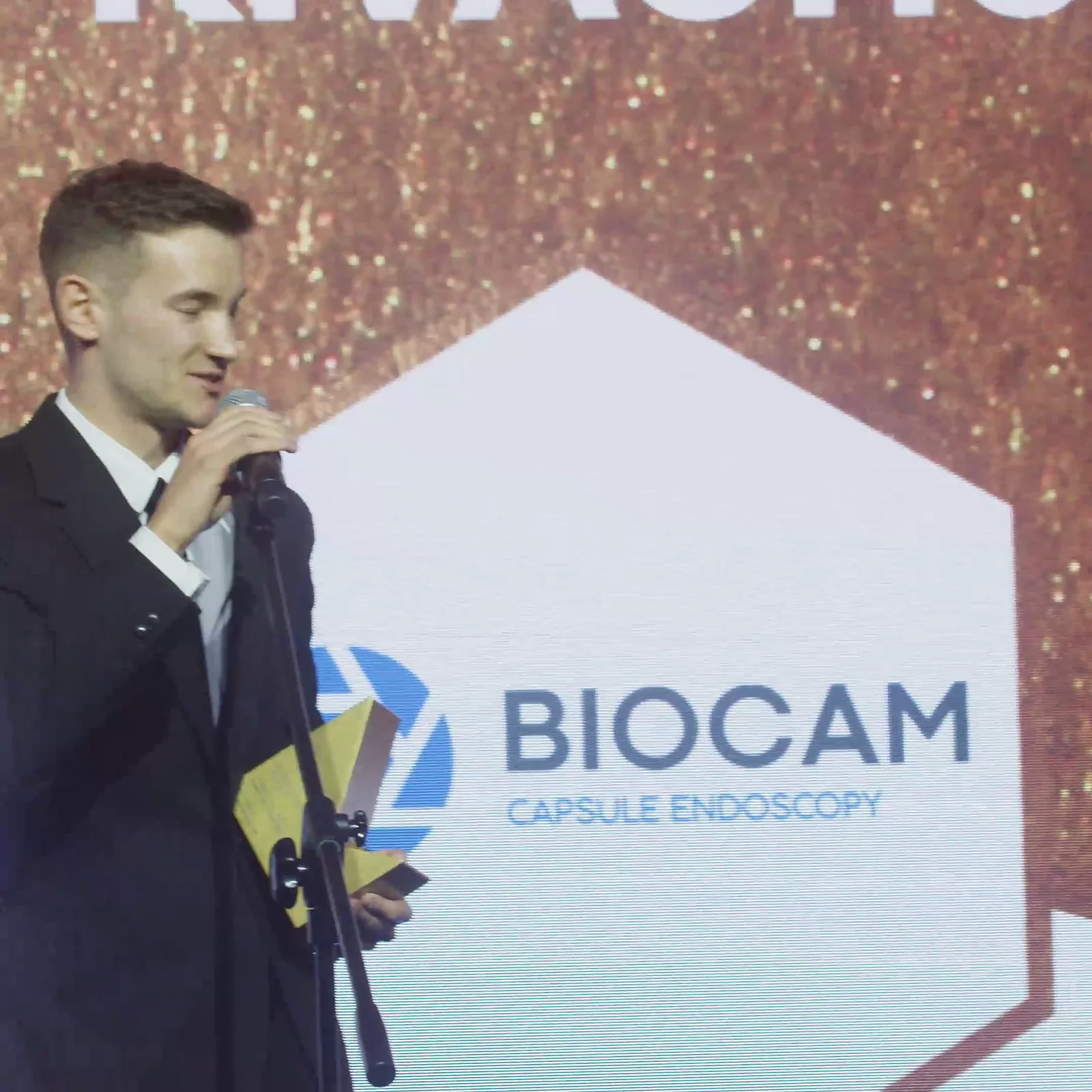 Młody laureat w czarnym garniturze dziękuje do mikrofonu, trzymając statuetkę — Gala DMR XII (2023)