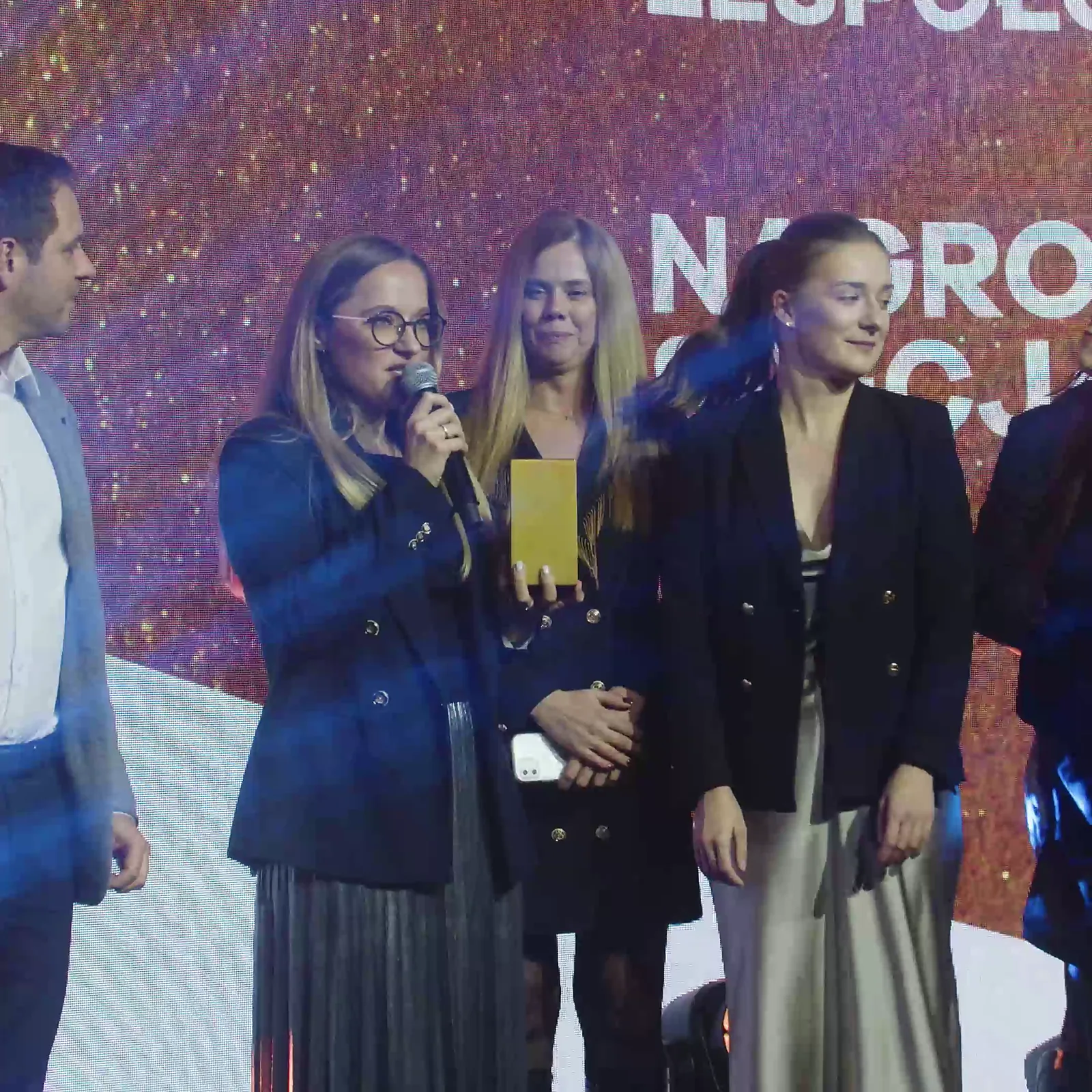 Laureatka w okularach przemawia w otoczeniu koleżanek z zespołu podczas wręczania Nagrody Specjalnej — Gala DMR XII (2023)