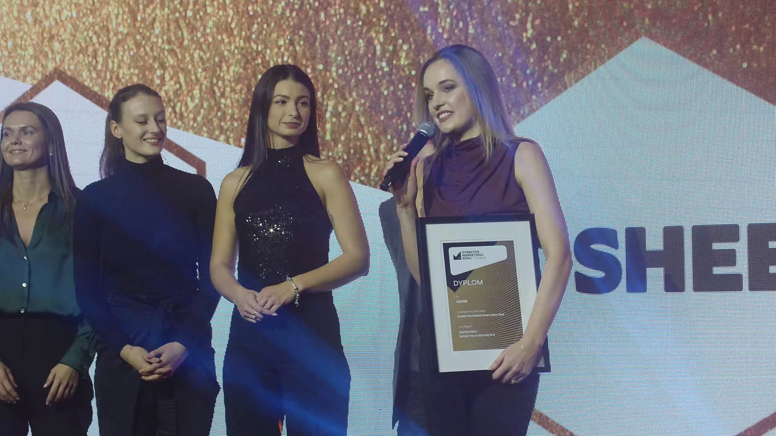 Laureatka w fioletowej bluzce mówi z dyplomem w dłoniach, obok stoją trzy koleżanki z zespołu — Gala DMR XII (2023)