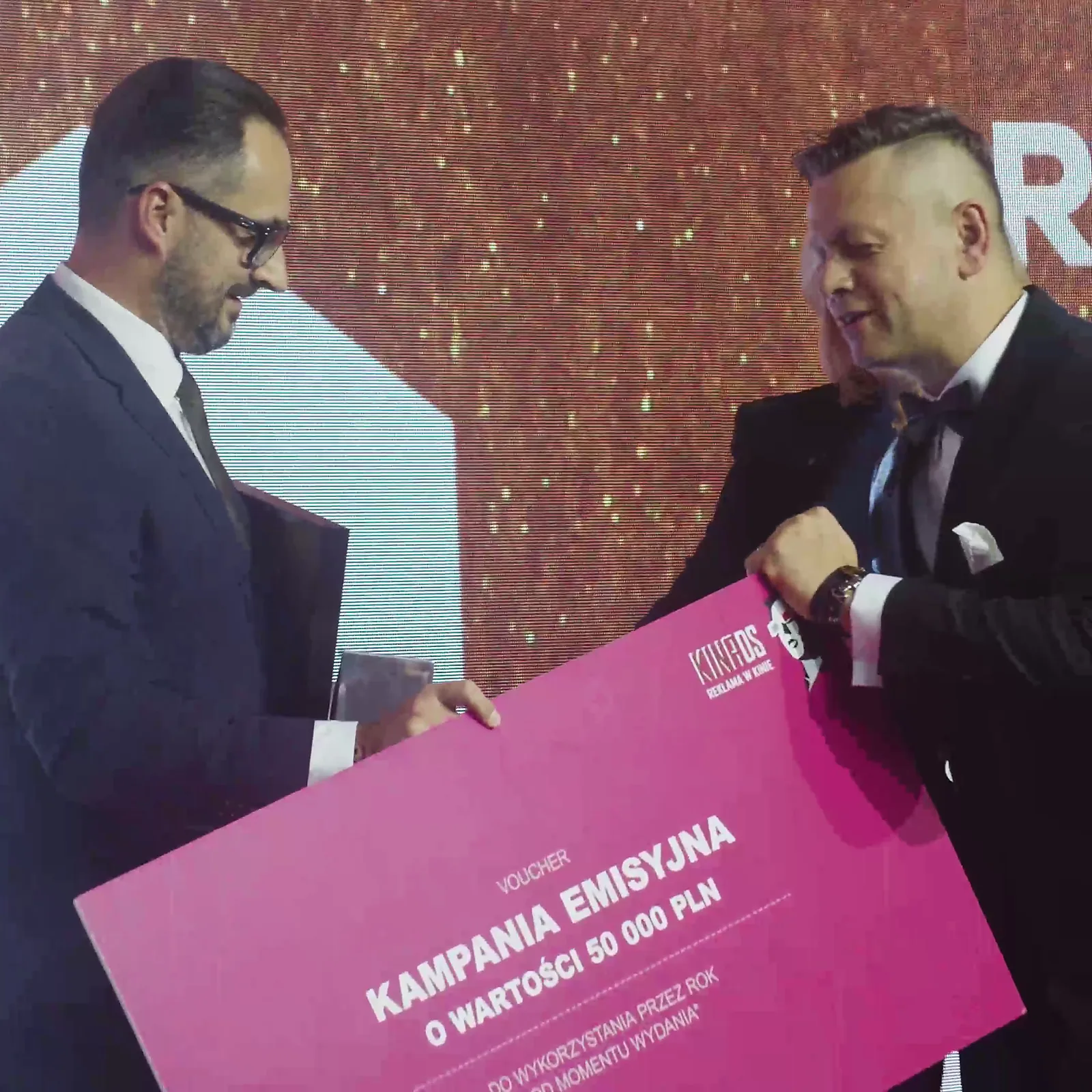 Laureat Grand Prix odbiera od prowadzącego duży różowy czek na kampanię reklamową — Gala DMR XII (2023)