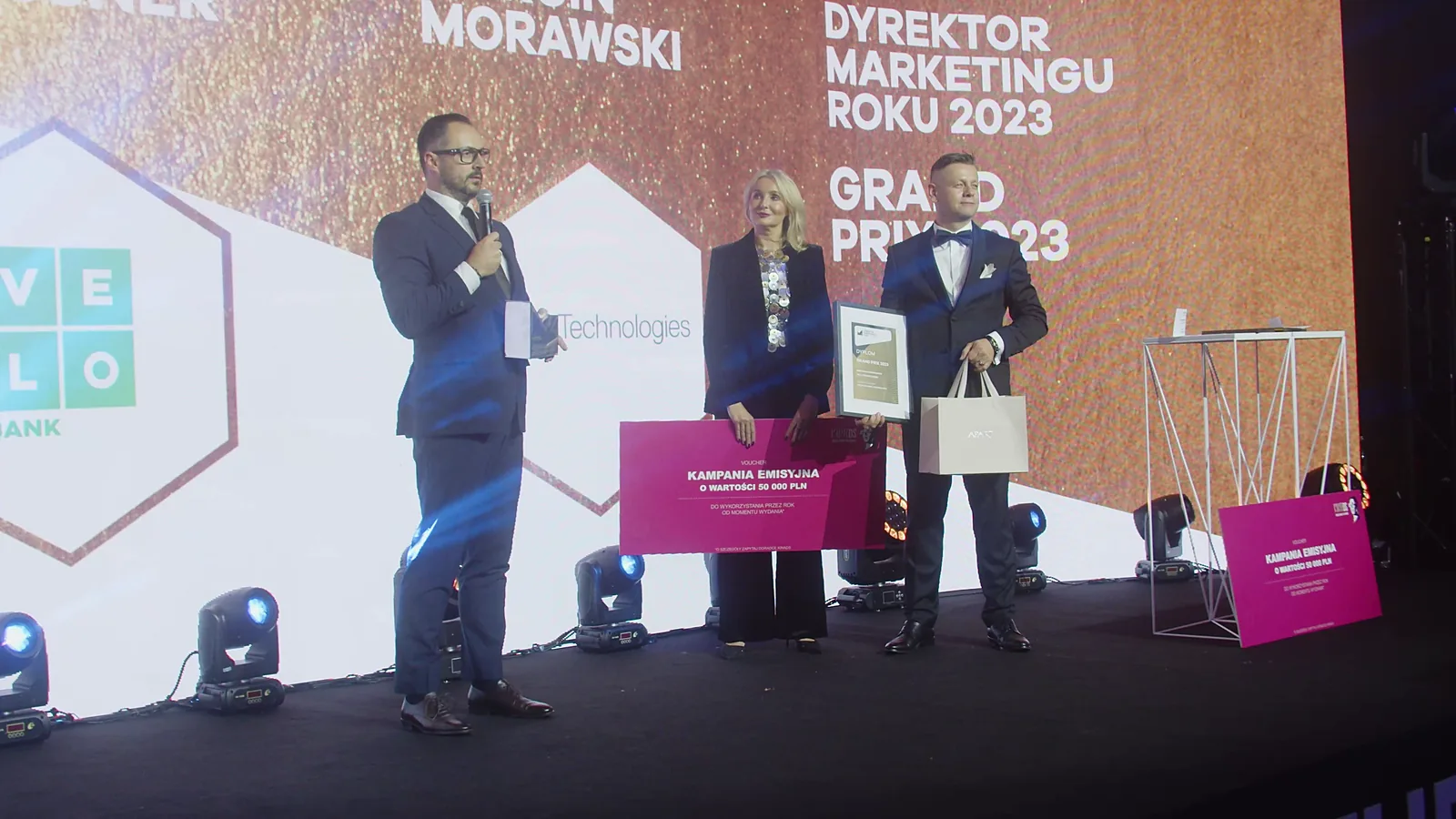 Szeroki kadr sceny: laureat Grand Prix przemawia, a prowadzący trzymają czek i dyplom — Gala DMR XII (2023)