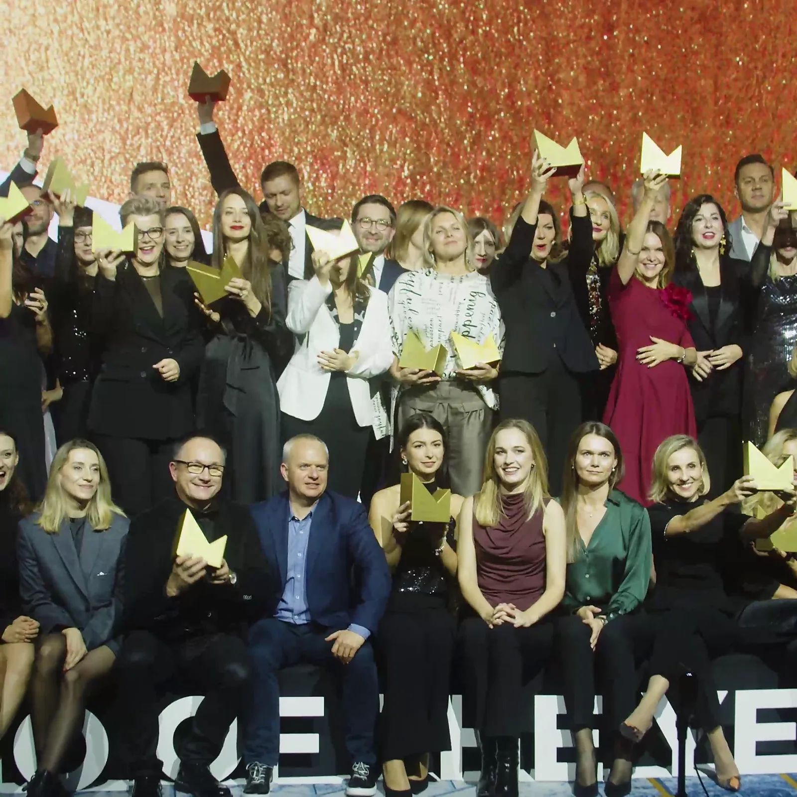 Laureaci unoszą złote statuetki wysoko w górę podczas wspólnego zdjęcia na scenie — Gala DMR XII (2023)
